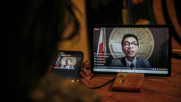 A resident of Antananarivo watches Madagascan President Andry Rajoelina address the nation via the Madagascan Presidency's Facebook page on October 13, 2025.