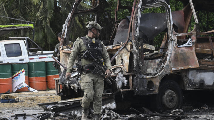 A police officer stands guard at the site where a bus exploded in front of a police station in Villa Rica, Cauca department, Colombia, on June 10, 2025.
