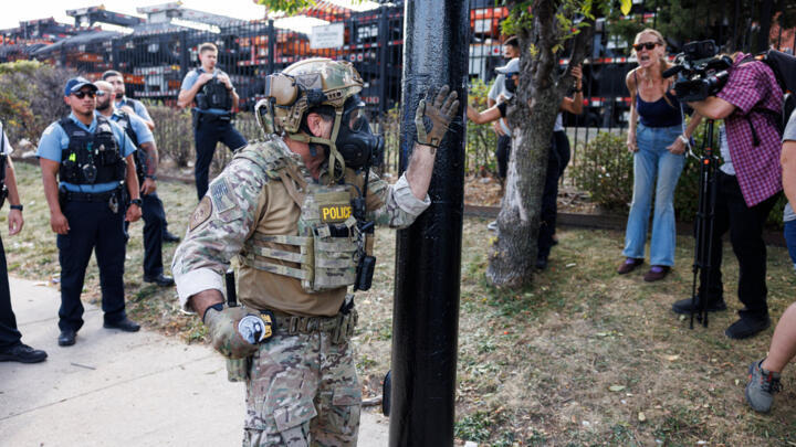 A DHS officer prepares to throw a gas canister in the Brighton Park neighborhood of Chicago, on October 4, 2025.
