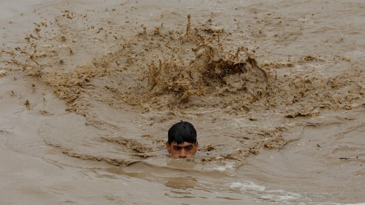 Un hombre nada en aguas producto de una inundación por lluvias, mientras se dirige a un terreno más alto, durante la temporada de monzones, en Charsadda, Pakistán, el 27 de agosto de 2022.