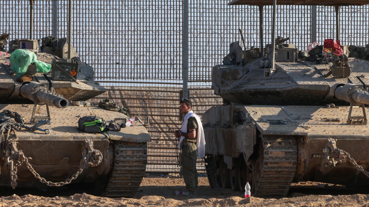 A soldier praying between stationed Israeli military armoured vehicles near the border fence with the besieged Palestinian territory on September 16, 2025.
