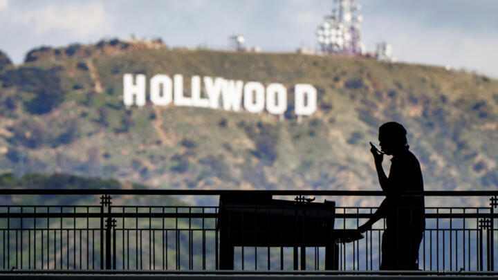 A worker wheels equipment past the famous Hollywood sign on March 8, 2023.