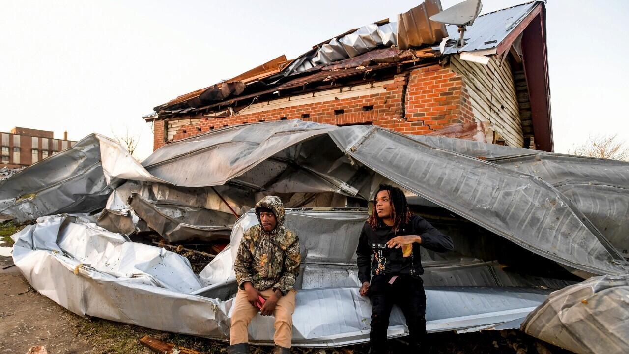 Dos personas se observan sobre un techo que voló de un edificio industrial y se envolvió alrededor de su casa después de que un tornado arrasara Selma, Alabama, EE.UU., el 12 de enero de 2023.