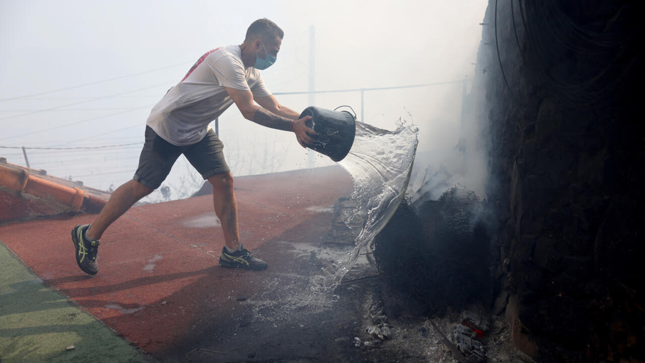 Un habitant de l'Estaque se bat contre les flammes avec un simple seau d'eau, le 8 juillet, alors qu'un violent incendie gagne du terrain dans ce quarter situé au bord de la mer.