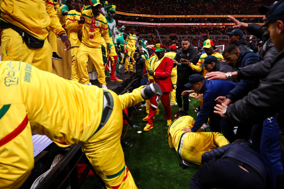 Angry Senegal fans are stopped from entering the pitch by security personnel