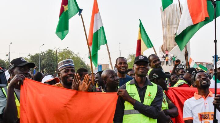 Supporters of the Alliance Of Sahel States (AES) hold up flags as they celebrate Mali, Burkina Faso and Niger leaving ECOWAS on January 28, 2024.