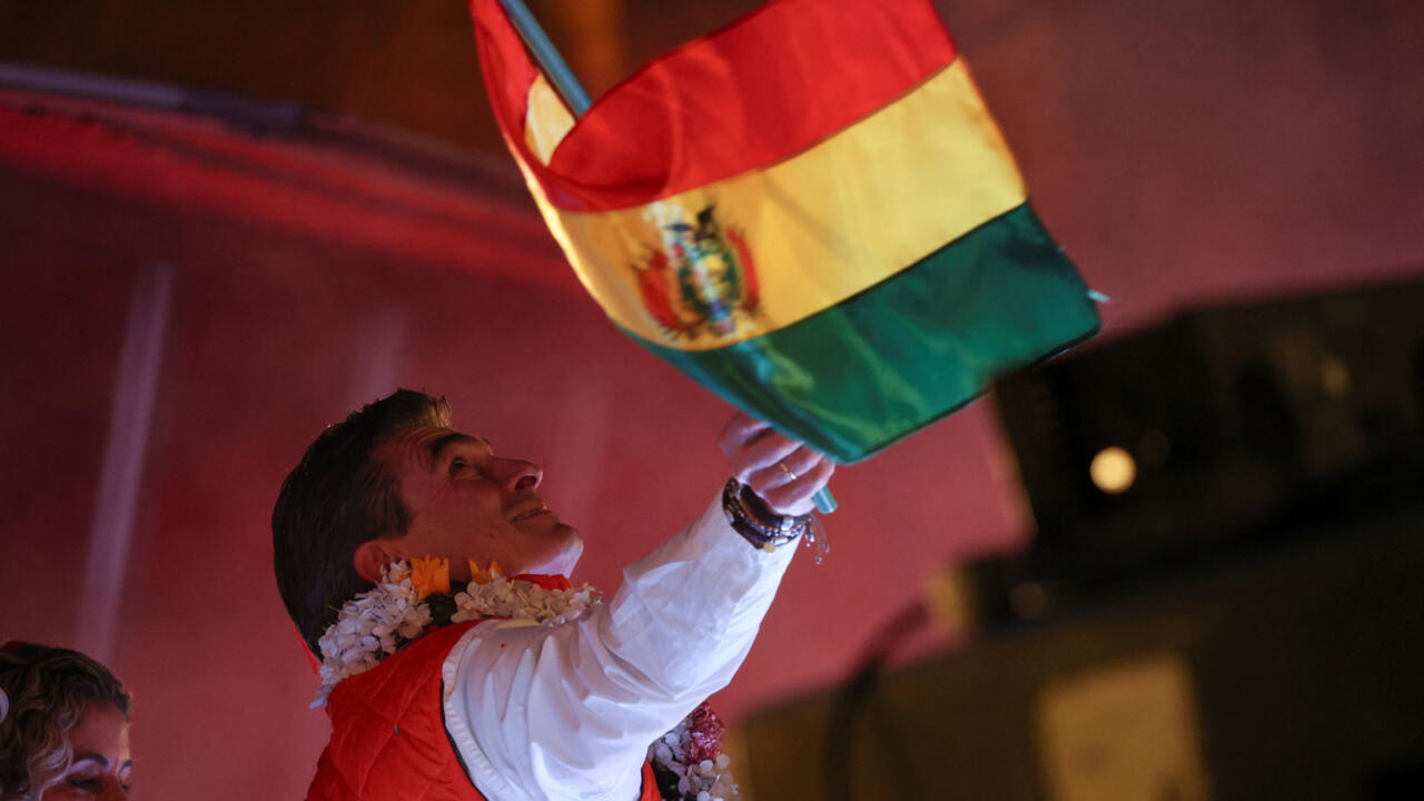 El senador centrista y candidato presidencial Rodrigo Paz, del Partido Demócrata Cristiano (PDC), ondea la bandera boliviana mientras celebra los resultados preliminares el día de la segunda vuelta de las elecciones presidenciales, en una calle de La Paz, Bolivia, el 19 de octubre de 2025.