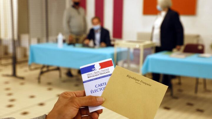A voter casts her ballot at a polling station in Cucq, northern France, for the first round of the French regional elections on June 20, 2021.