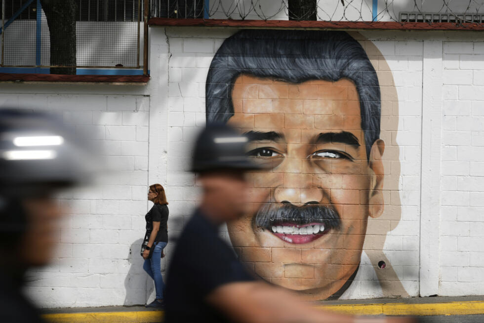 Un mural del presidente venezolano Nicolás Maduro cubre una pared de la calle mientras pasan motociclistas en Caracas, Venezuela, el jueves 5 de junio de 2025.