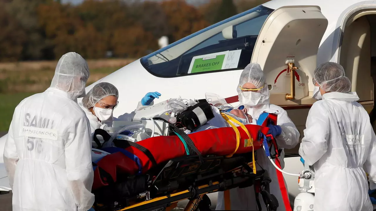 Medical staff members move a Covid-19 patient from a plane at Vannes Airport in western France on November 2, 2020.