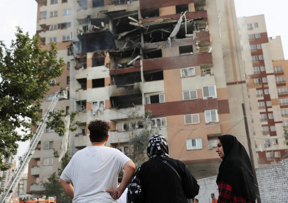 Des habitants observent un immeuble endommagé à la suite de frappes israéliennes, à Téhéran, en Iran, le 13 juin 2025.