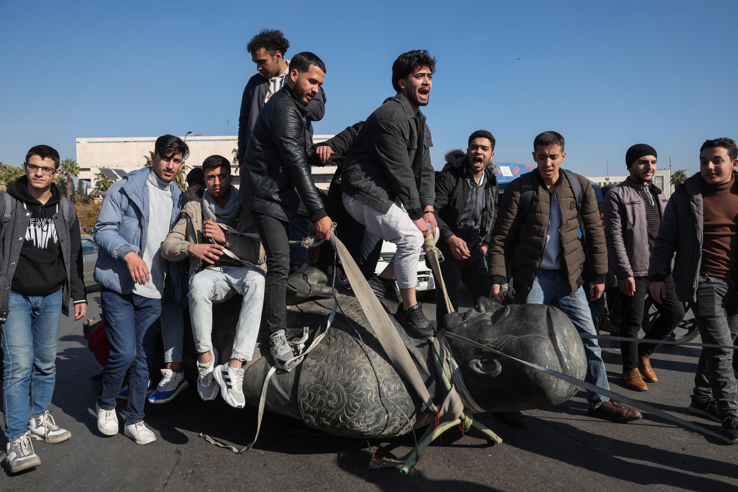 Des étudiants sur une statue détruite de l'ancien président Hafez al-Assad, père du président déchu, près du campus de l'université de Damas, le 15 décembre 2024.