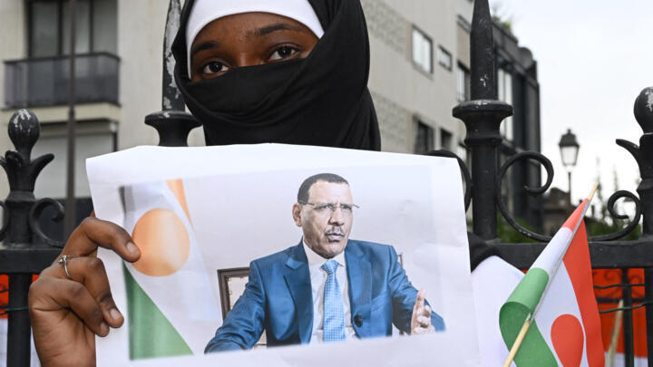 A woman holds the image of ousted Nigerien President Mohamed Bazoum during a protest outside the Nigerien embassy in Paris on August 5, 2023.