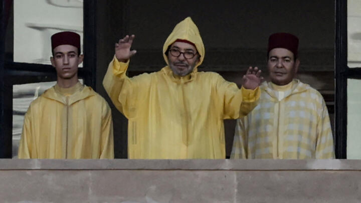 Morocco's King Mohammed VI (centre), accompanied by his son, Crown Prince Moulay Hassan (left) appears on the balcony of the Parliament headquarters in Rabat on October 10, 2025.