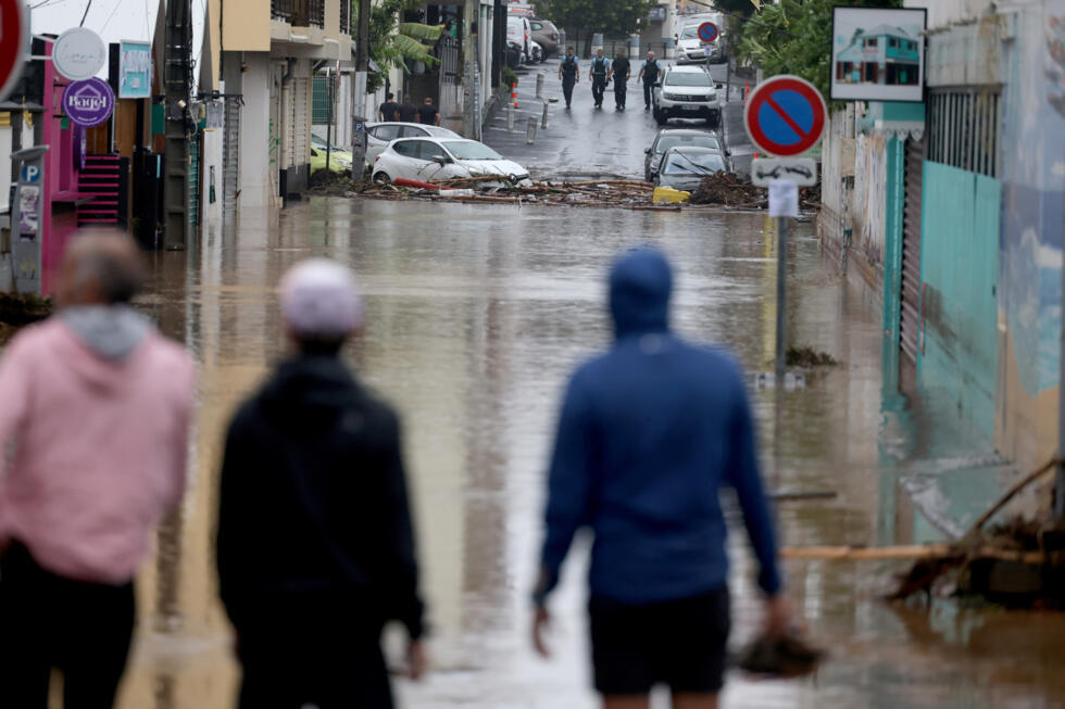 Des piétons et des de la gendarmes sur une route inondée à Saint-Paul de La Réunion, le 28 février 2025