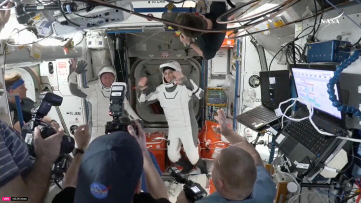 Butch Wilmore and Suni Williams wave at the hatch of a SpaceX Crew Dragon capsule before closing th