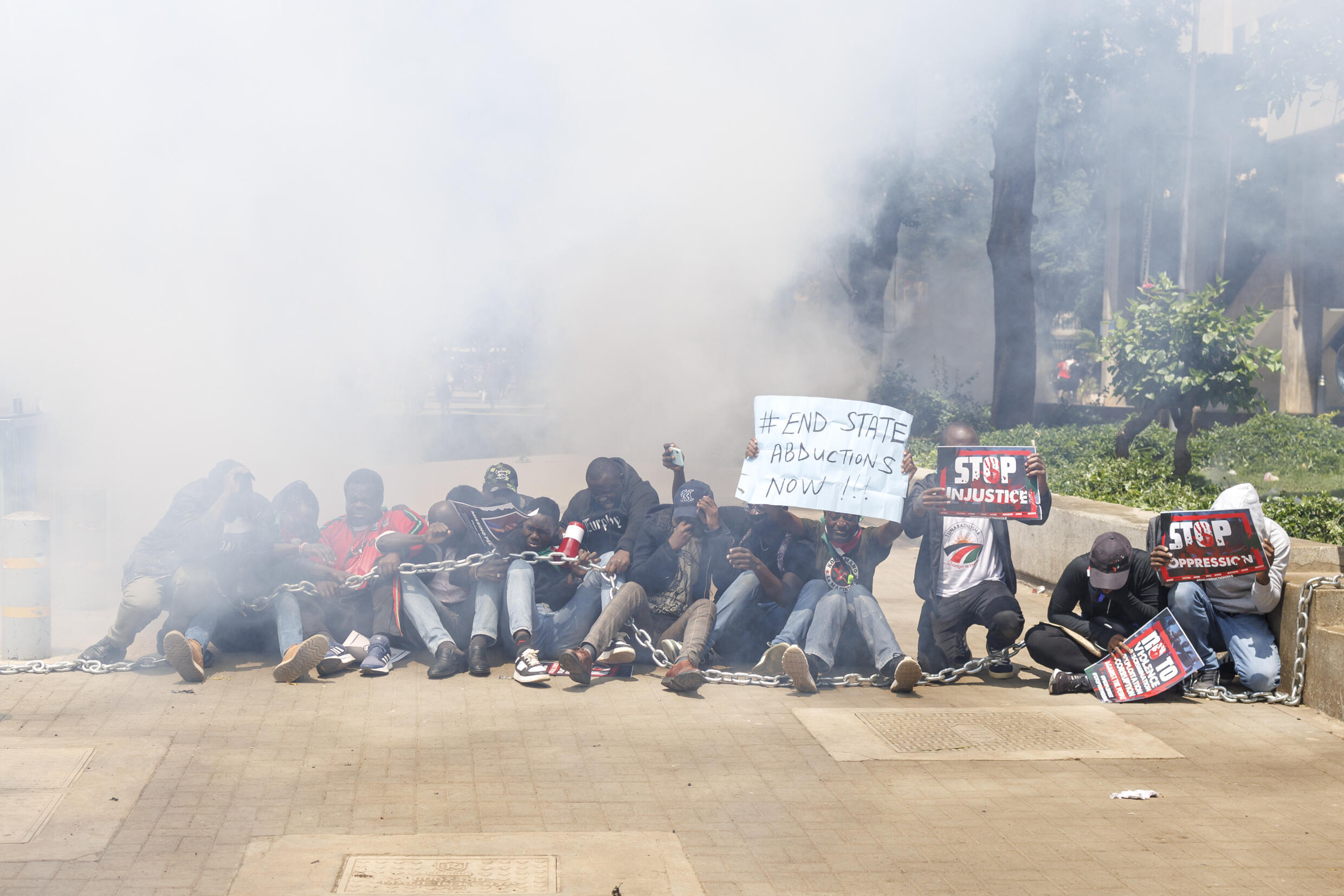 Un nuage de gaz lacrymogène enveloppe les manifestants qui se préparent au sol à une confrontation avec la police anti-émeute alors qu'ils exigent la libération des personnes prétendument enlevées par