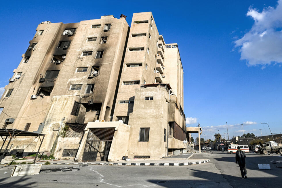 People walk outside the prison facility run by the 'Palestine Branch' of Syria's Military Intelligence Directorate in Damascus on December 13, 2024. Days after the fall of Bashar al-Assad, pe