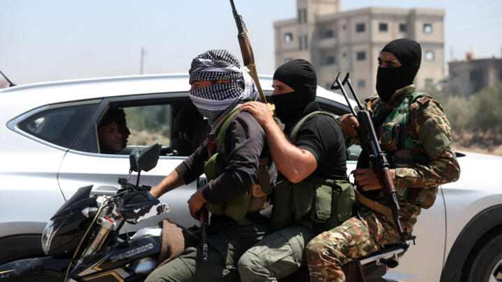 Fighters from Bedouin tribes ride a motorcycle in al-Mazraa village, in Syria's southern Sweida governorate, as clashes with Druze gunmen continue on July 18, 2025.