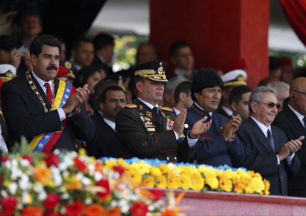 El presidente de Venezuela, Nicolás Maduro, a la izquierda, el comandante estratégico operacional, general Vladimir Padrino López, el presidente de Bolivia, Evo Morales, y el presidente de Cuba, Raúl Castro, aplauden durante un desfile militar en conmemoración del primer aniversario de la muerte del expresidente de Venezuela, Hugo Chávez, en Caracas, Venezuela, el 5 de marzo de 2014.