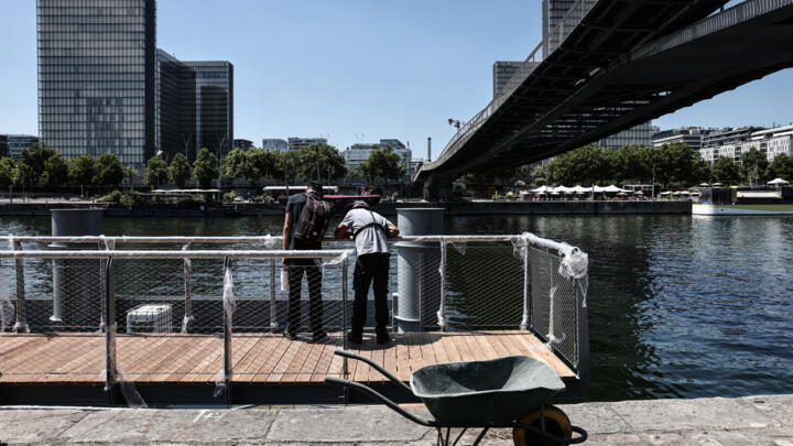Workers construct the floating pontoon that will form part of the future safe swimming area in the Seine river, in Paris on June 30, 2025.
