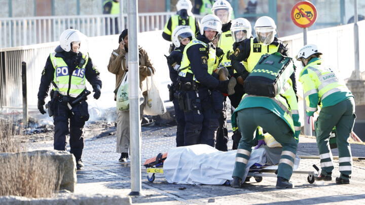 Police and ambulance personnel carry an injured man who was shot in the leg during rioting in Norrkoping, Sweden, April 17.