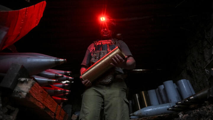 Ukrainian serviceman carries ammunition for a self-propelled howitzer as he prepares it to fire towards Russian troops at a position near a front line in Donetsk region