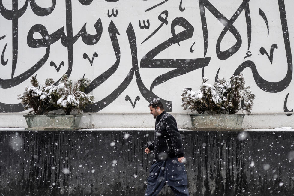 An Afghan man walks past a wall with Arabic inscriptions during snowfall in Kabul, Afghanistan on January 22.