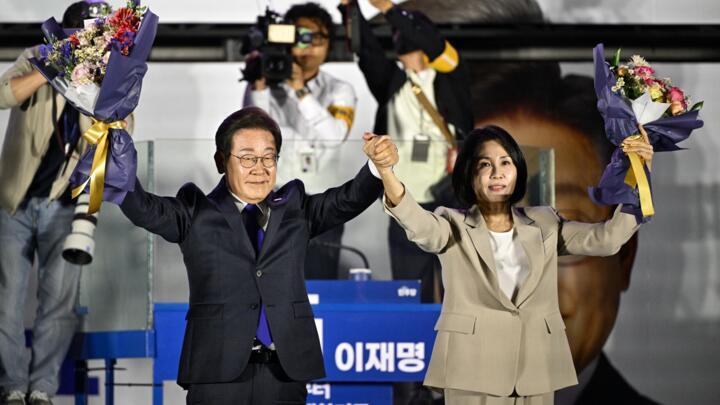 Lee Jae-myung (L) the presidential candidate for South Korea's Democratic Party, and his wife Kim Hye-gyeong (R) acknowledge the crowd as they await the final results of the presidential election.