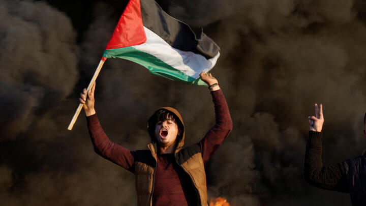 A man holds a Palestinian flag during clashes with Israeli forces near the Israel-Gaza border east of Gaza City, January 26, 2023.