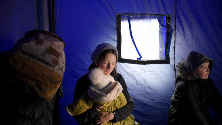 [File photo] A refugee fleeing the conflict from neighbouring Ukraine holds her baby as she sits in a tent at the Romanian-Ukrainian border on February 26, 2022.