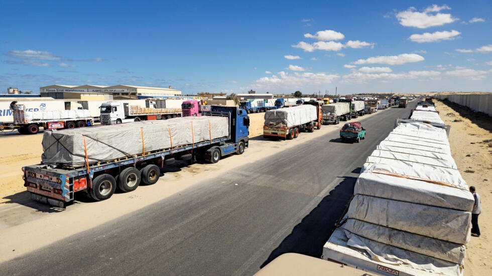 Des camions transportant l'aide humanitaire préparée par le Croissant-Rouge égyptien attendent d'entrer dans la bande de Gaza par le poste-frontière de Rafah, à Al-Arish en Égypte, le 14 octobre 2025.