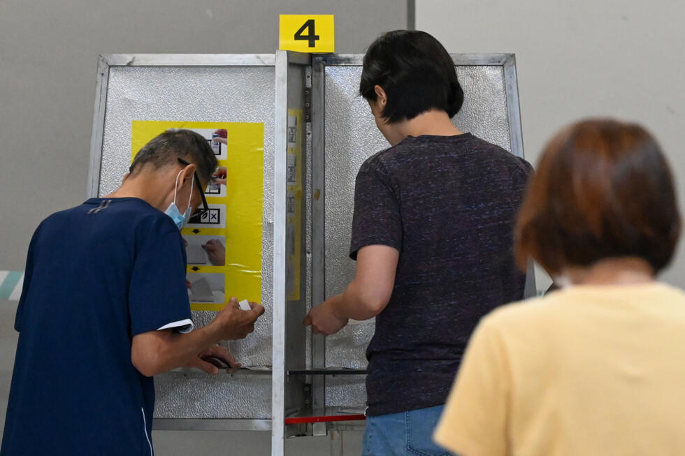 Des électeurs choisissent leur bulletin de vote pour les élections législatives, à Singapour le 3 mai 2025.