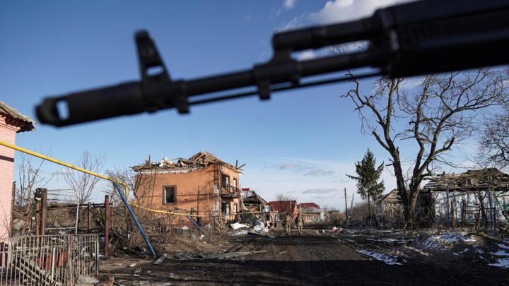 Russian soldiers walk past destroyed houses in the village of Kazachya Loknya, which was previously held by Ukrainian troops and recently retaken by Russia's armed forces, on March 18, 2025