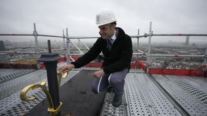 French President Emmanuel Macron touches the top of the newly rebuilt spire and cross, during his visit to the reconstruction work at Notre-Dame de Paris Cathedral, on the Ile de la Cite in Paris.
