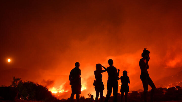 Residents look at flames as a wildfire rages near Palaia Fokaia, some 45 Km south of Athens, on August 8, 2025.