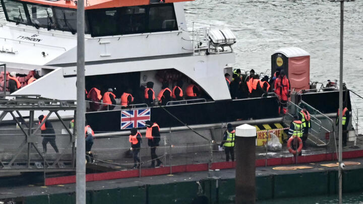 Migrants picked up at sea attempting to cross the English Channel from France, disembark from Border Force vessel 'Typhoon' after it arrived at the Marina in Dover, southeast England, on January 13, 2