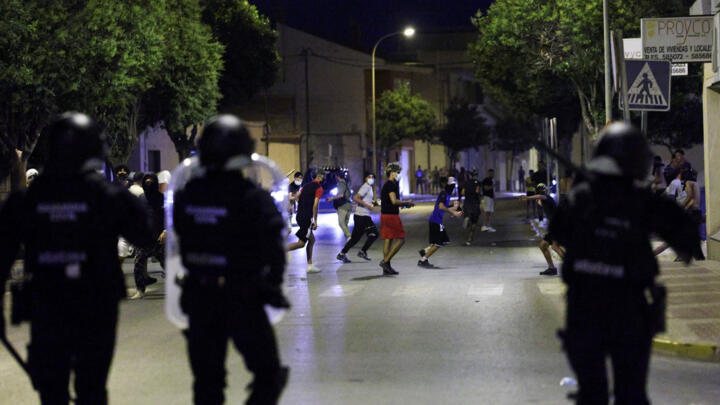 People run on a street during clashes with police, amid anti-migrant unrest following an attack on an elderly man by unknown assailants earlier in the week, in Torre Pacheco, Spain, July 13, 2025. 