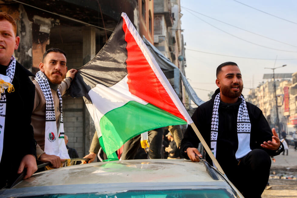 Des hommes accompagnent une voiture où flotte le drapeau palestinien, à Gaza-ville le 19 janvier 2025