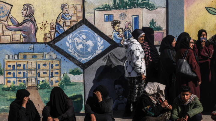 Displaced Palestinians queue to receive aid at the United Nations Relief and Works Agency for Palestine Refugees (UNRWA) centre in Rafah on January 28, 2024.