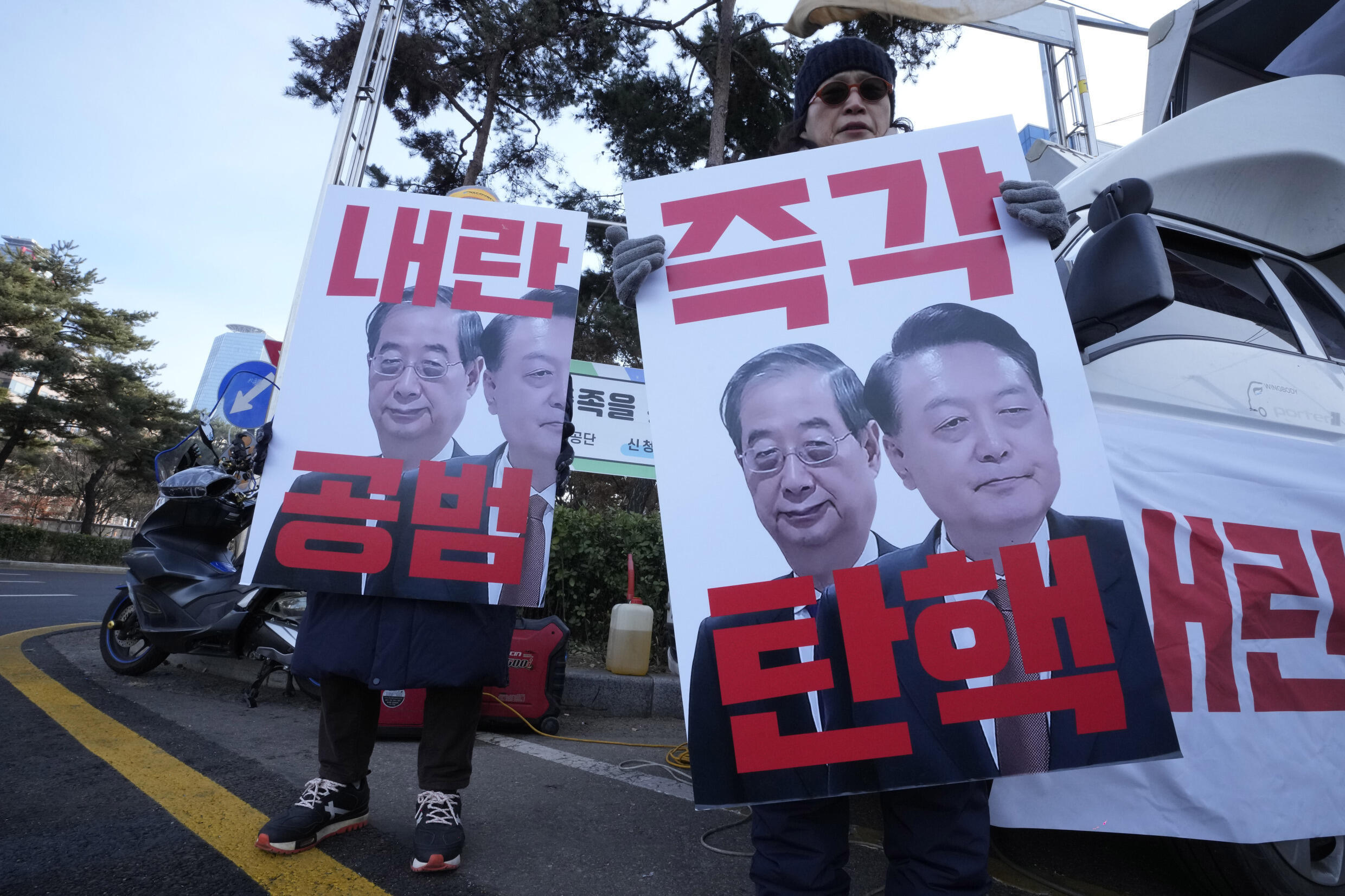 Manifestantes sostienen pancartas con imágenes del presidente destituido Yoon Suk Yeol, a la derecha, y del presidente en funciones Han Duck-soo durante una concentración para exigir la destitución de Han frente a la Asamblea Nacional en Seúl, Corea del Sur, 27 de diciembre de 2024. En los carteles se puede leer «Juicio político inmediato».