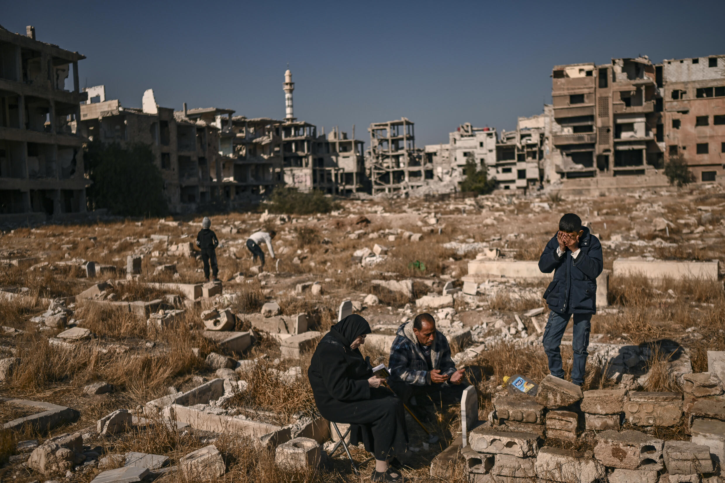 Des gens prient au cimetière du camp ravagé de réfugiés palestiniens à Yarmouk, dans le sud de Damas, le 14 décembre 2024.