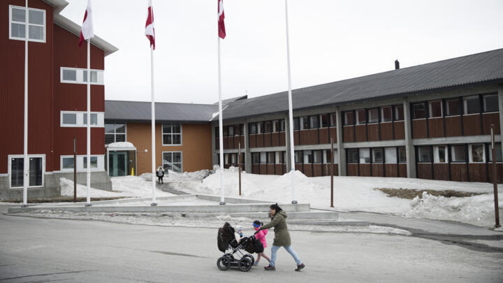 Une femme et ses enfants passent devant la salle du conseil du comté du Groenland dans les rues de Nuuk, au Groenland, le 19 avril 2018.