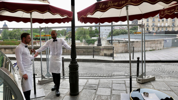 Waiters stand behind a barrier waiting for customers at Le Flore en L'ile restaurant on the Ile Saint-Louis in Paris, France, on July 18, 2024.