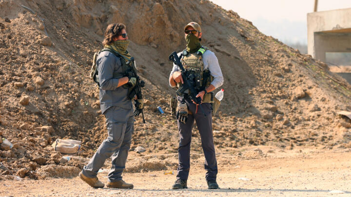 Armed men stand guard at a checkpoint manned by US and Egyptian security at the Netzarim Corridor in the Gaza Strip on January 29, 2025.