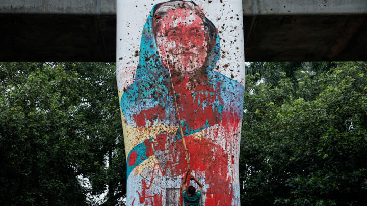 A protester vandalises a mural of then-Bangladeshi Prime Minister Sheikh Hasina with paint during protests that eventually led to her downfall, in Dhaka on August 3, 2024.