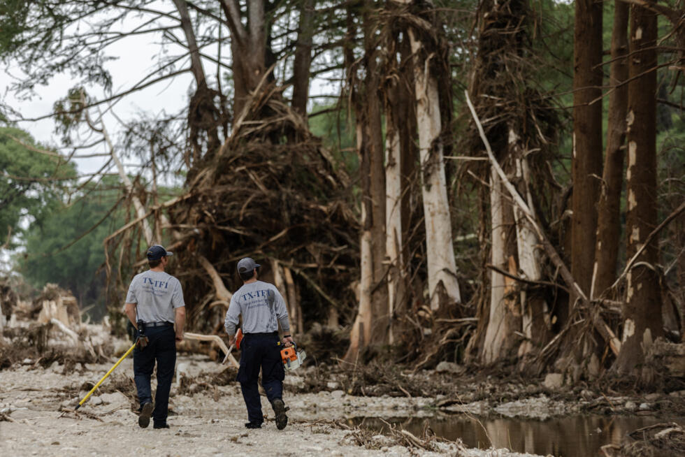 Equipos de búsqueda y rescate caminan entre escombros en busca de sobrevivientes o restos de víctimas arrastrados por la inundación repentina del 7 de julio de 2025 en Hunt, Texas.