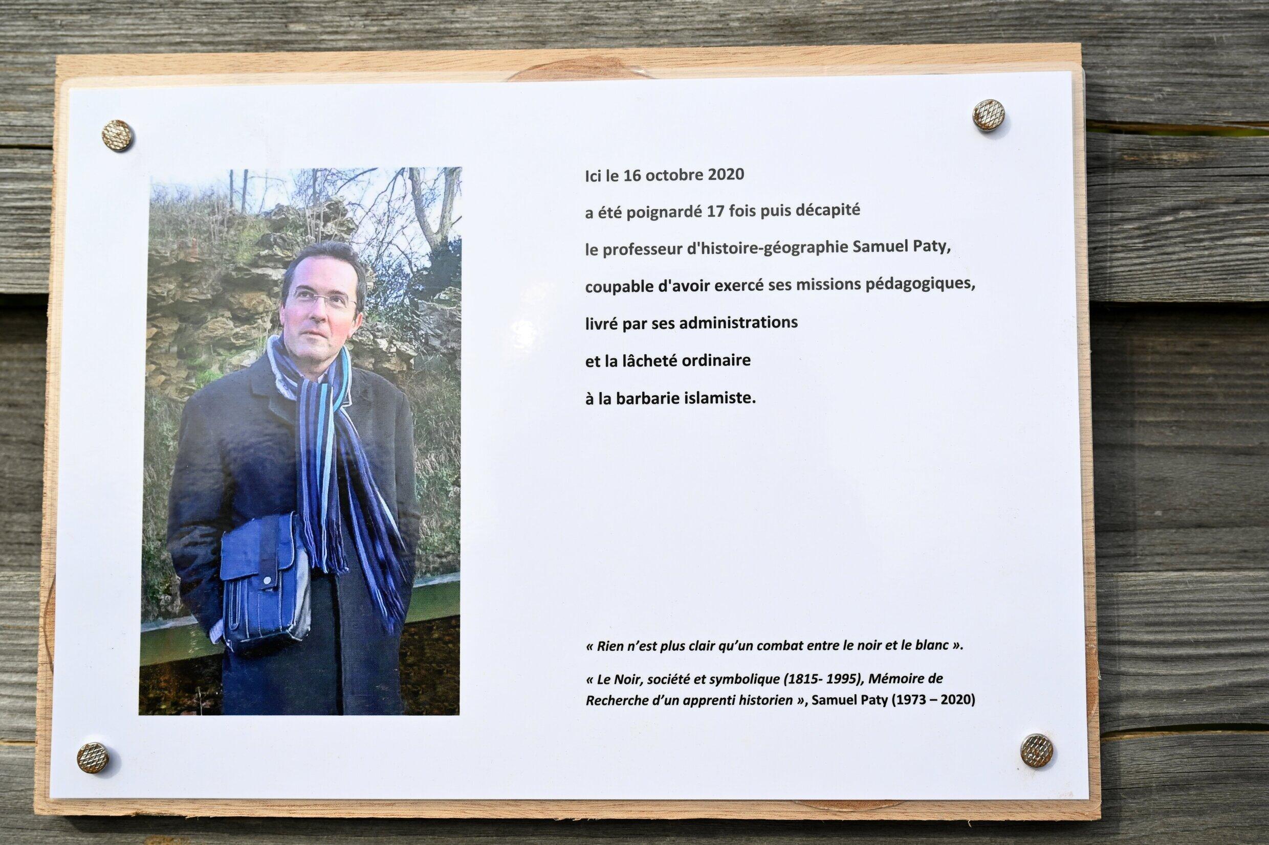 Photographie prise le 16 octobre 2023 d'une plaque commémorative pour l'enseignant assassiné Samuel Paty (portrait) près de l'école du Bois d'Aulne à Conflans-Sainte-Honorine, en banlieue parisienne.