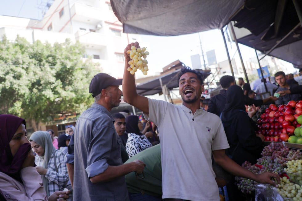 Un vendeur brandit une grappe de raisins sur un marché à Deir el-Balah, dans le centre de la bande de Gaza, plus d’une semaine après l’entrée en vigueur d’un accord de cessez-le-feu entre Israël et le Hamas, le 18 octobre 2025