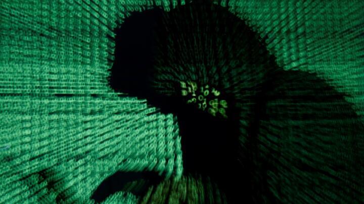 FILE PHOTO: A man holds a laptop computer as cyber code is projected on him in this illustration picture taken on May 13, 2017. 